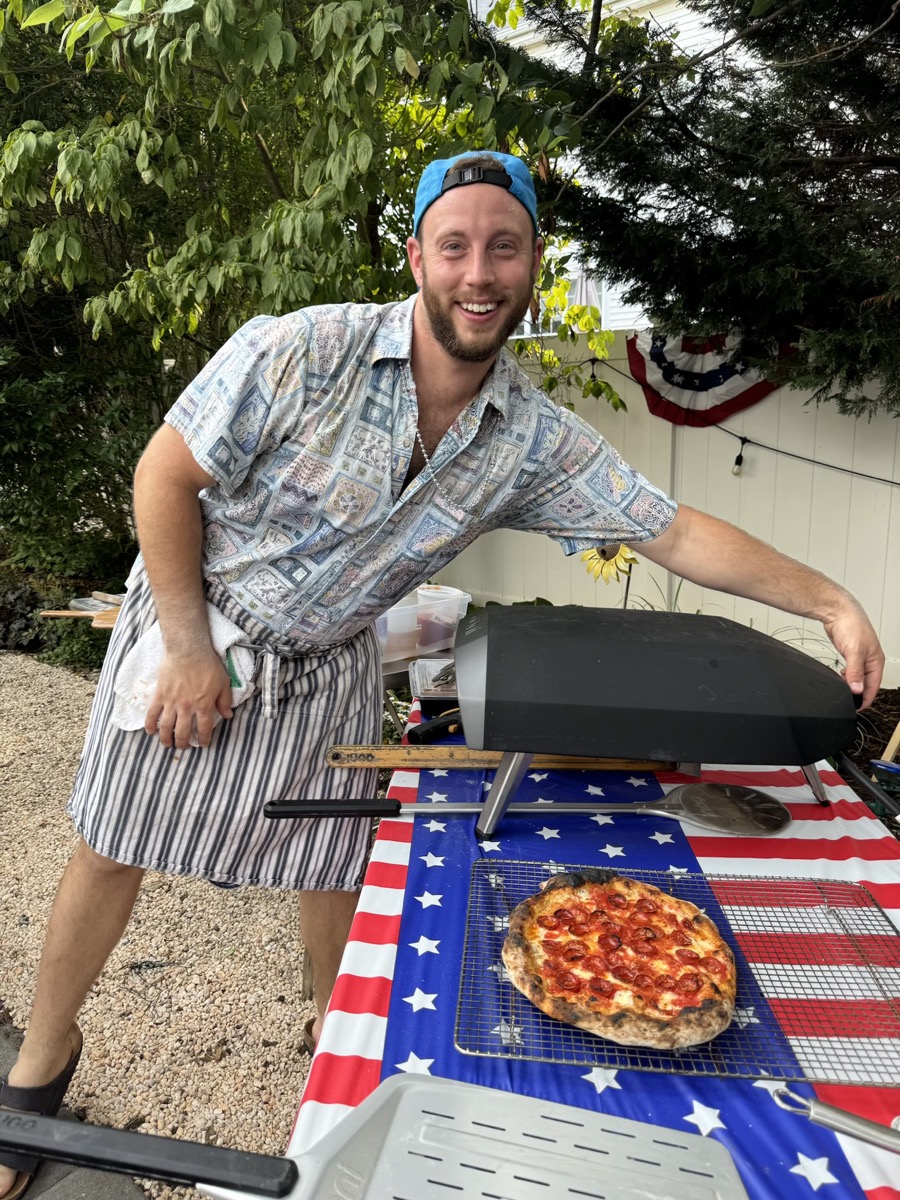 Lonny at outdoor Ooni grill with American flag setup